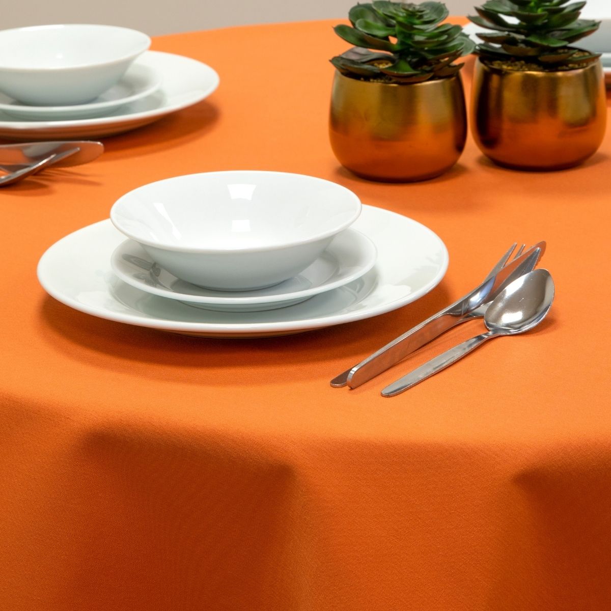dining table with orange table cloth and cutlery